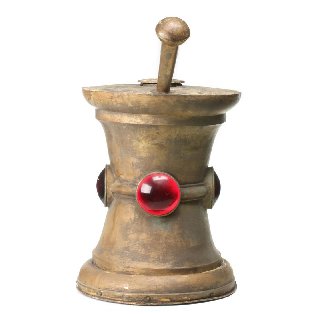A LARGE, LIGHTED MORTAR & PESTLE APOTHECARY TRADE SIGN: The hollow zinc model of mortar and pestle with three large glass cabochon 'jewels', old gilt finish with traces of light gold sheen showing through, original wood base. the trade sign is depicted her