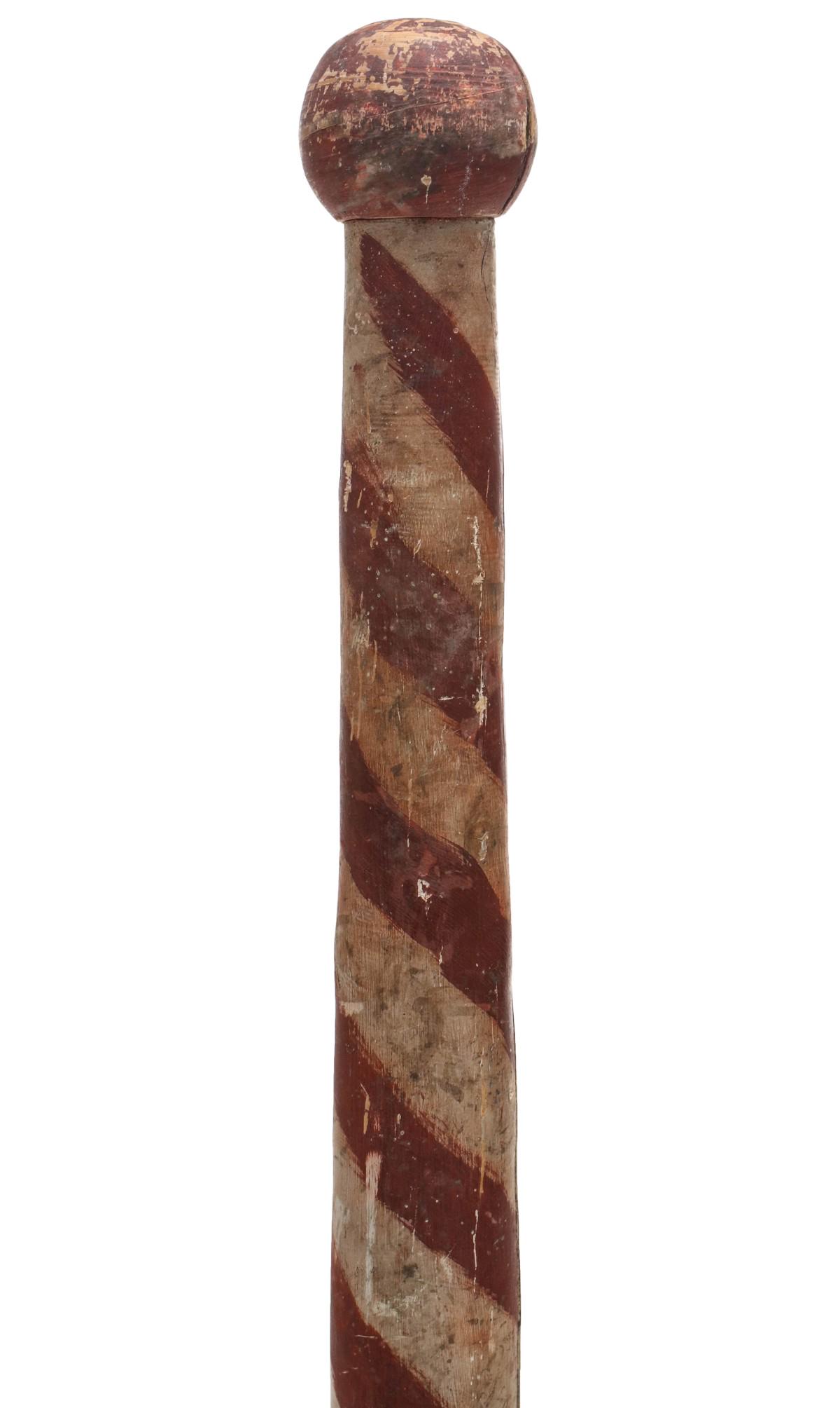 A PRIMITIVE RED AND WHITE UPRIGHT BARBER POLE C. 1900: The 55-inch tapering wood pole painted red and white and mounted on turned wood base in old blue paint. A note on the underside of the base confirms the period. Measures 55 x 6 inches. Provenance: The
