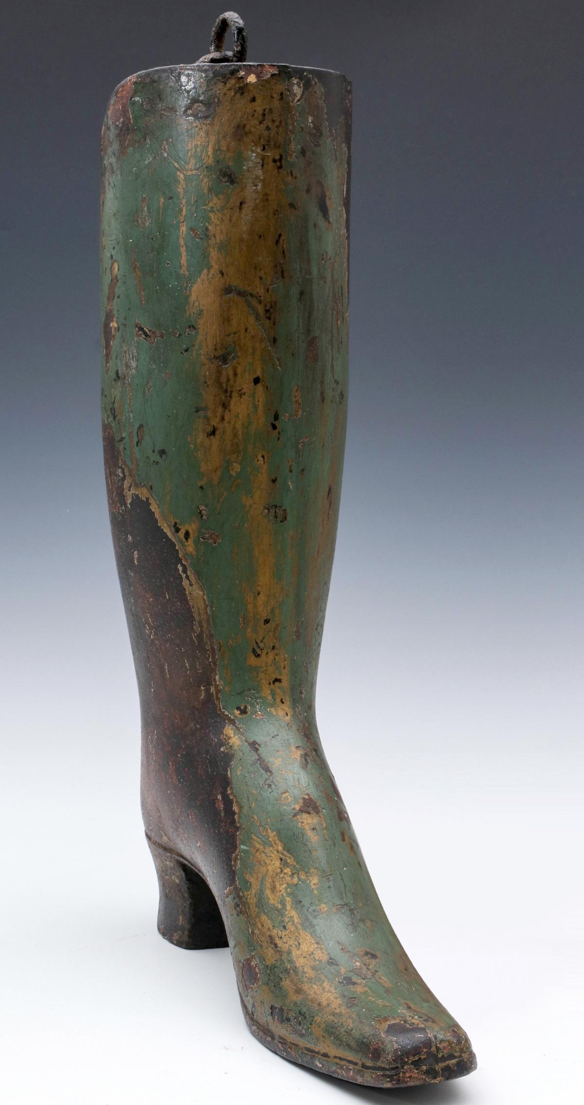 A 19TH CENTURY PAINTED IRON BOOT MAKER'S TRADE SIGN: The hollow cast iron depiction of a 19th century dandy's Wellington boot, remnant gilding covered by old green paint, areas of exposed iron, remnant hanging apparatus, fine character and appeal. Measu
