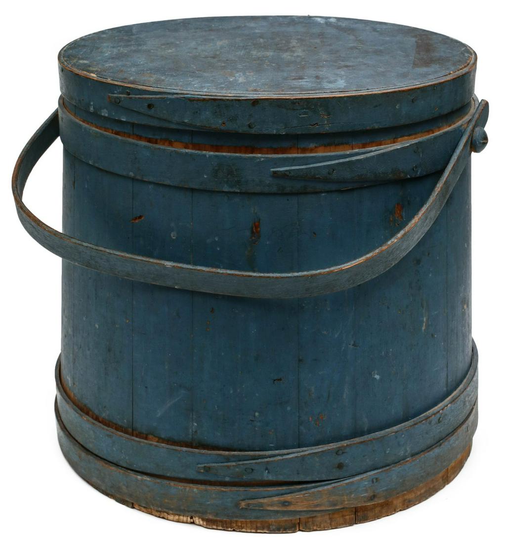 A 19TH CENTURY FIRKIN IN ORIGINAL BLUE MILK PAINT: Tongue and groove staves bound in wood bands with finger laps, bentwood bail handle affixed with a wooden peg, original blue paint. Measures 14 x 15.5 x 15.5 inches. Provenance: The Jerry and Cathy Mu