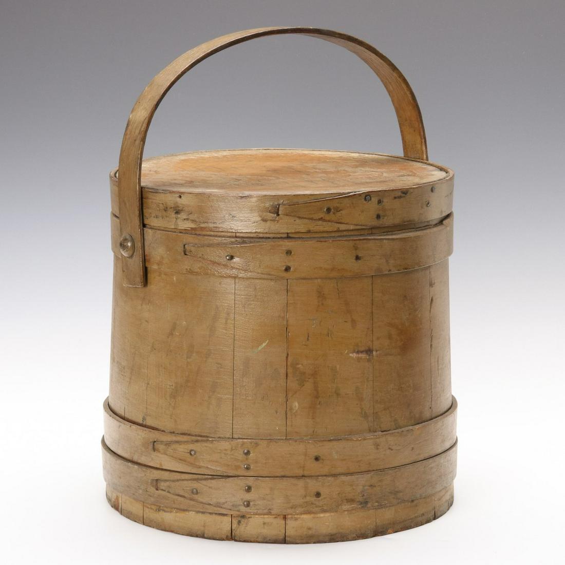 A 19TH CENTURY PAINTED WOOD FIRKIN: The tongue and groove wood staves bound in finger lap bands, copper tacks, bentwood bail handle on wooden peg, signed 'Gibson - on the lid. Measures 1.75 x 12.5 x 13 inches. Provenance: The Jerry and