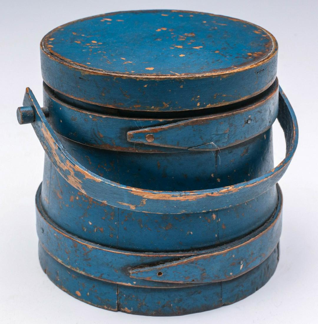 A SMALL 19TH CENTURY FIRKIN IN BRILLIANT BLUE PAINT: The thick wood staves bound in wood bands with finger laps, bentwood bail handle on wooden peg, great old blue milk paint in an interesting blue. Measures 5 x 6 x 5.5 inches. Provenance: The Jerry and