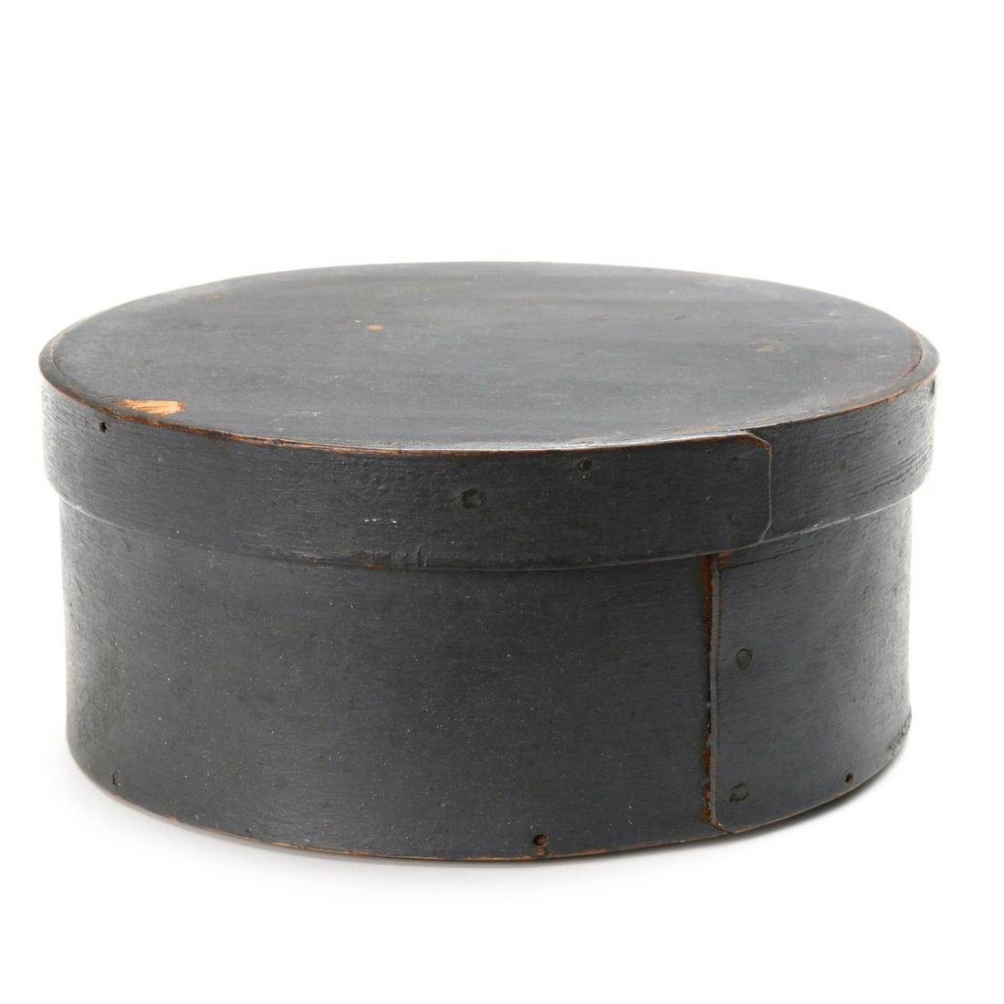 A 19TH CENTURY BENTWOOD PANTRY BOX IN OLD GRAY PAINT: The circular box in old milk paint, with straight seams, constructed with rosehead nails and wood pegs. Measures 3 x 6.75 inches. Provenance: The Jerry and Cathy Mueller Collection, Sioux City, Iowa W