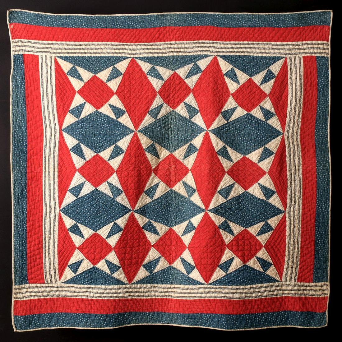 A 19TH C. RED, WHITE AND BLUE 'IOWA STAR' CRIB QUILT: The 'Iowa Star' pattern in red, white and blue calico fabrics with various print patterns including white stars on blue; framed in three borders, hand pieced and quilted, white binding and backing. Me