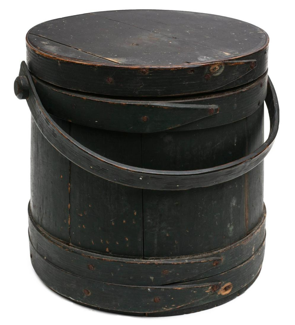 A 19TH C. FIRKIN IN GOOD OLD DRY GREEN PAINTED SURFACE: The wood staves bound in finger lap wood bands, iron tacks, bentwood bail handle on wooden peg, an early example in old dry dark green paint with oxidation and interesting surface. Measures 10.75 x 11