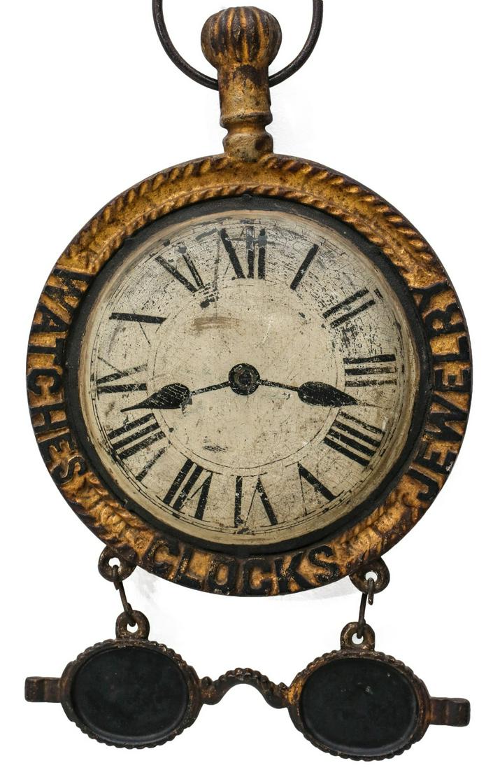 A GOOD WATCHMAKER'S TRADE SIGN WITH FIGURAL SPECTACLES: The two-sided pocket watch trade sign with fancy coined edge iron frame advertising JEWELRY, CLOCKS, WATCHES at 3,6 and 9 cast with tabs for suspending a pair of cast iron eye glasses; the detailed sh