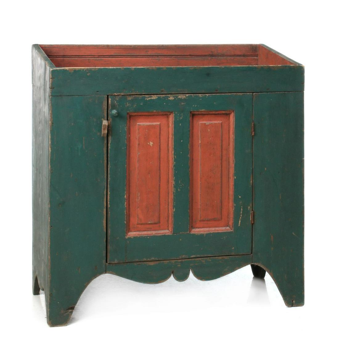 A NEW ENGLAND DRY SINK IN GREEN PAINT WITH BITTERSWEET: The pine case with lively front and side cut-outs, outstanding original dry painted surfaces of green and bittersweet, raised panel doors, the interior with original green paint, beaded back splash bo