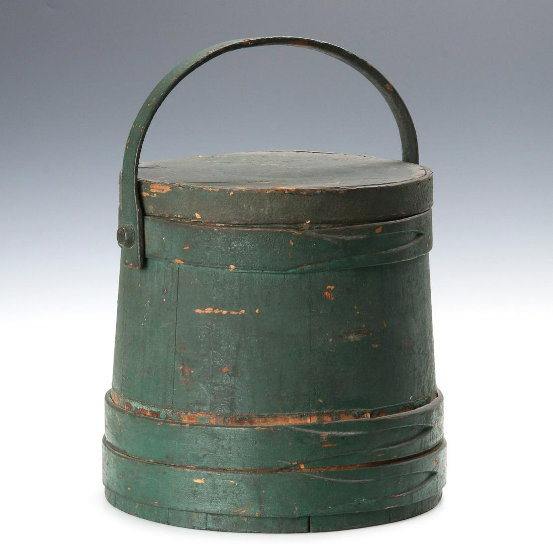 A 19TH CENTURY FIRKIN IN ORIGINAL DRY GREEN PAINT: The tongue and groove wood staves bound in wood bands with interlaced finger laps, bentwood bail handle affixed with a wooden peg, great dry old surface with crusty veil on old green paint. Measures 1