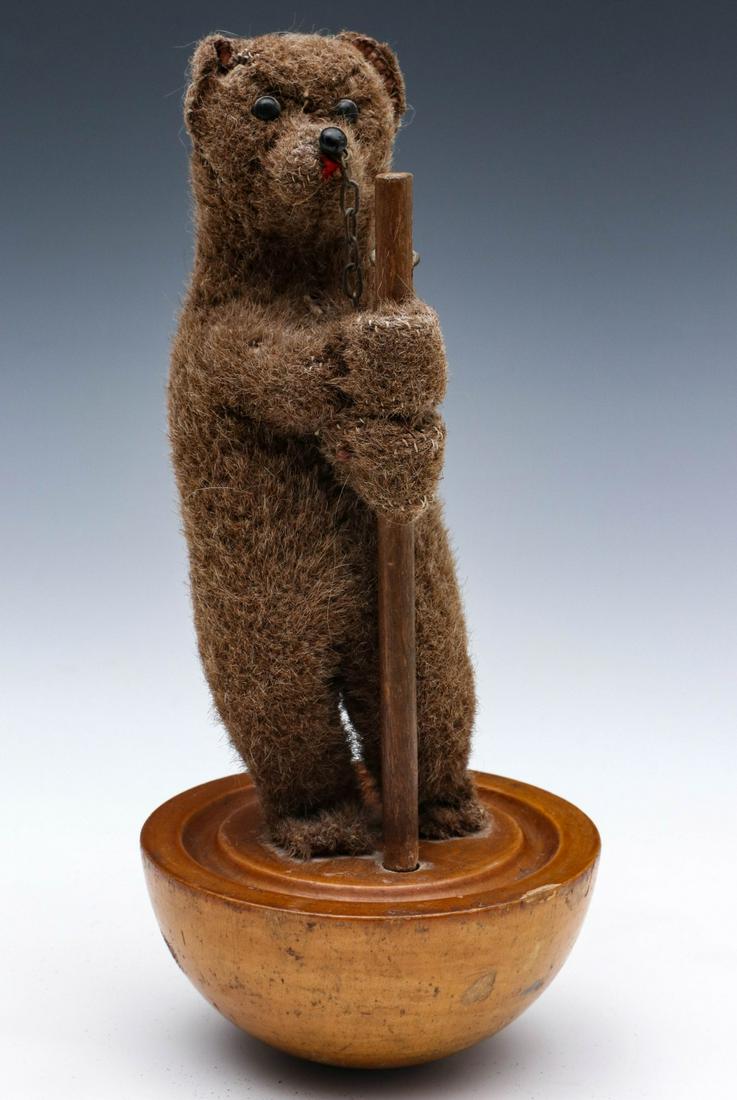 A VERY RARE, ORIGINAL STEIFF TUMBLING BEAR CIRCA 1906: The standing bear covered in worsted wool holding stick and standing on a rounded base, shoe button eyes, black nose with chain, red felt tongue, blank button in the proper left ear from the 1905-06 p