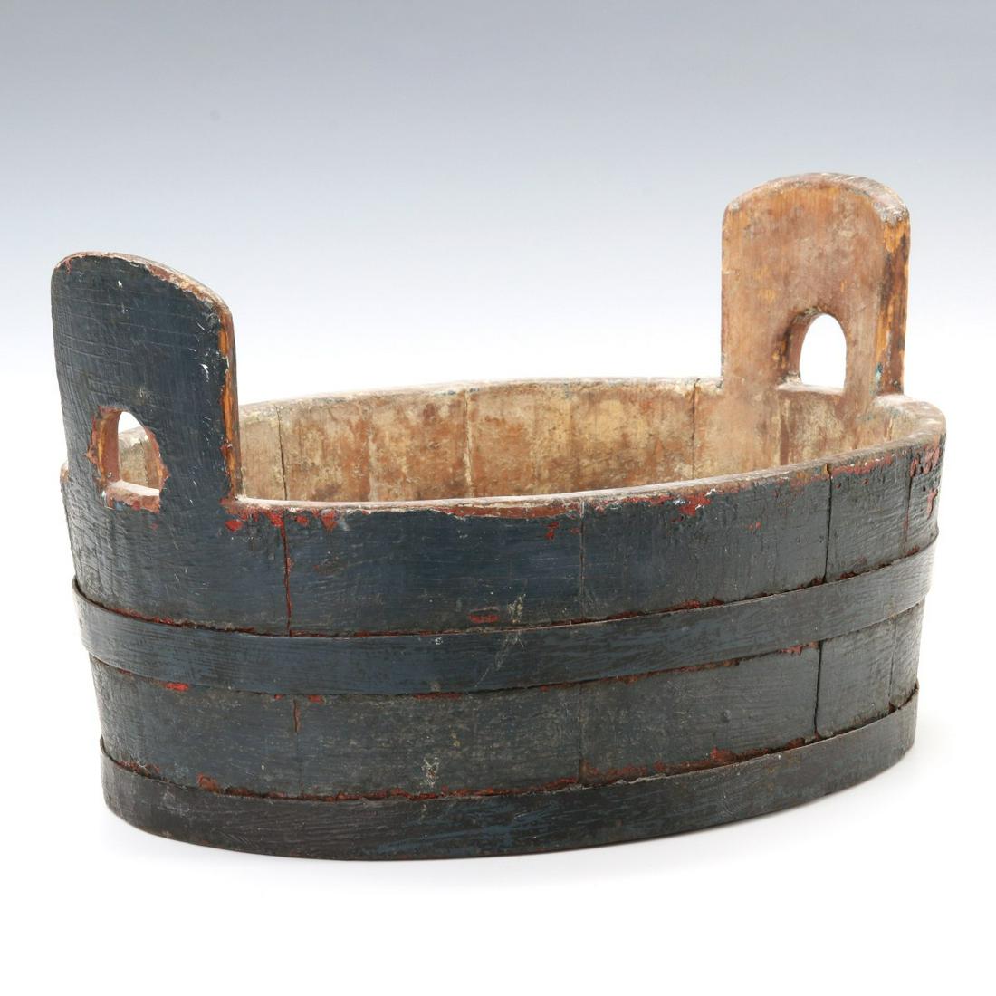 A 19TH C. PAINTED SHAKER TYPE WASH TUB IN OLD PAINT: The treen keeler with piggin handle each end, stave construction with forged iron bands and rivets, great crusty surfaces inside and out, the interior with cream-colored buttermilk paint, the wood and