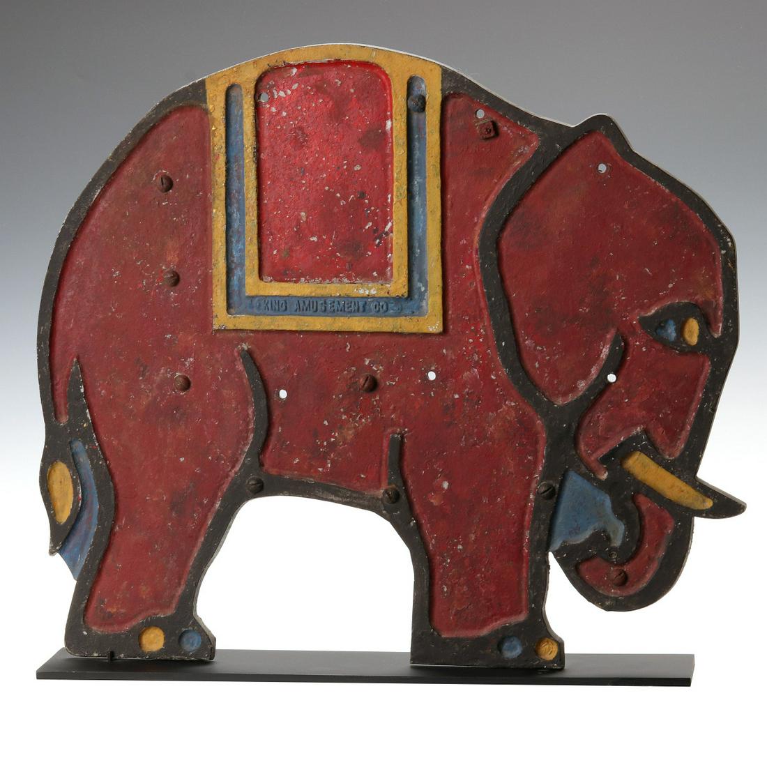 A COLORFUL ART DECO INFLUENCE FIGURAL ELEPHANT MARQUEE: The whimsical design of an elephant with circus blanket, bright colors with black outline, lettered KING AMUSEMENT CO in the casting, this being the front or marquee only from a game or other King Amu