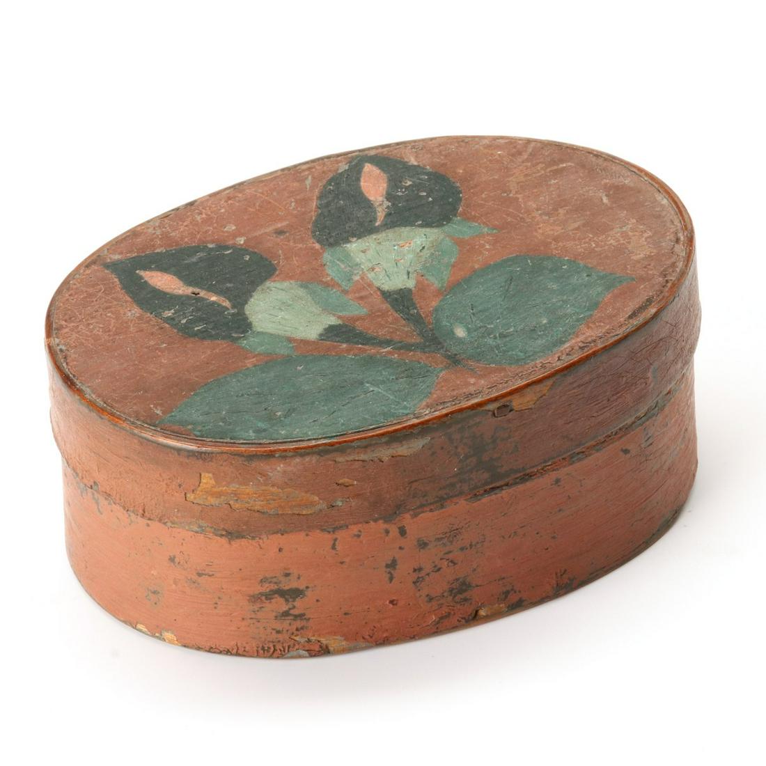 A DECORATED 19TH C. OVAL PANTRY BOX IN SALMON PAINT: The oval box with thin walls, wood peg construction, iron tacks on swallow tail bands and good original salmon paint with dry patinated surface along with period decoration of folky Jack-in-the-Pulpit