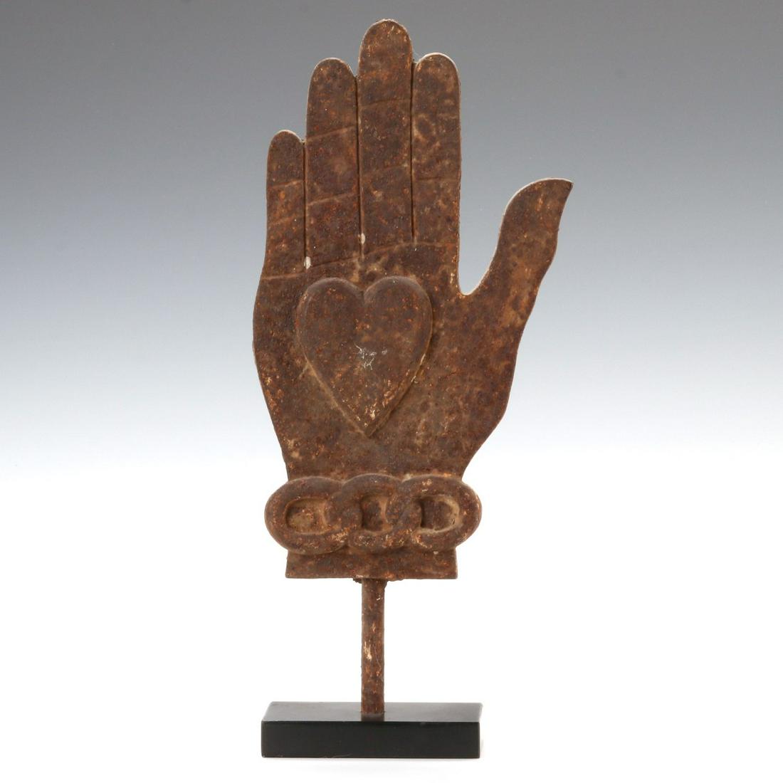A CAST IRON ODD FELLOWS HEART AND HAND SYMBOL C. 1890: The hand with heart and three linked rings representing friendship, love, and truth most commonly associated with the Odd Fellows fraternal organization. Displayed on custom iron stand. Measures 14 x 