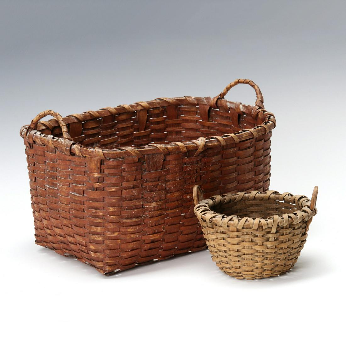 TWO GOOD CIRCA 1900 SPLINT BASKETS, ONE IN RED STAIN: The deep rectangular form basket with splint handles and old red stain; plus a bowl form with carved wood handles. Measures 2.75 x 4.75 and 5.5 x 11 x 8.5 inches. We happily provide seamless in-house 