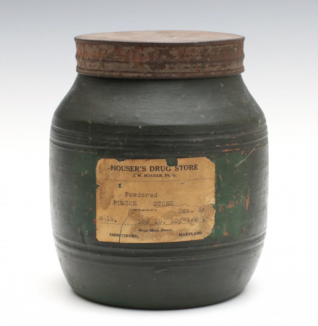 A 19TH CENTURY REDWARE STORAGE JAR IN OLD GREEN PAINT: The cylindrical form with concave neck and sloped shoulder, rows of concentric incised lines, nice old green paint darkened with age and exposure, a druggist's paper label for Powdered Pumice Stone. M