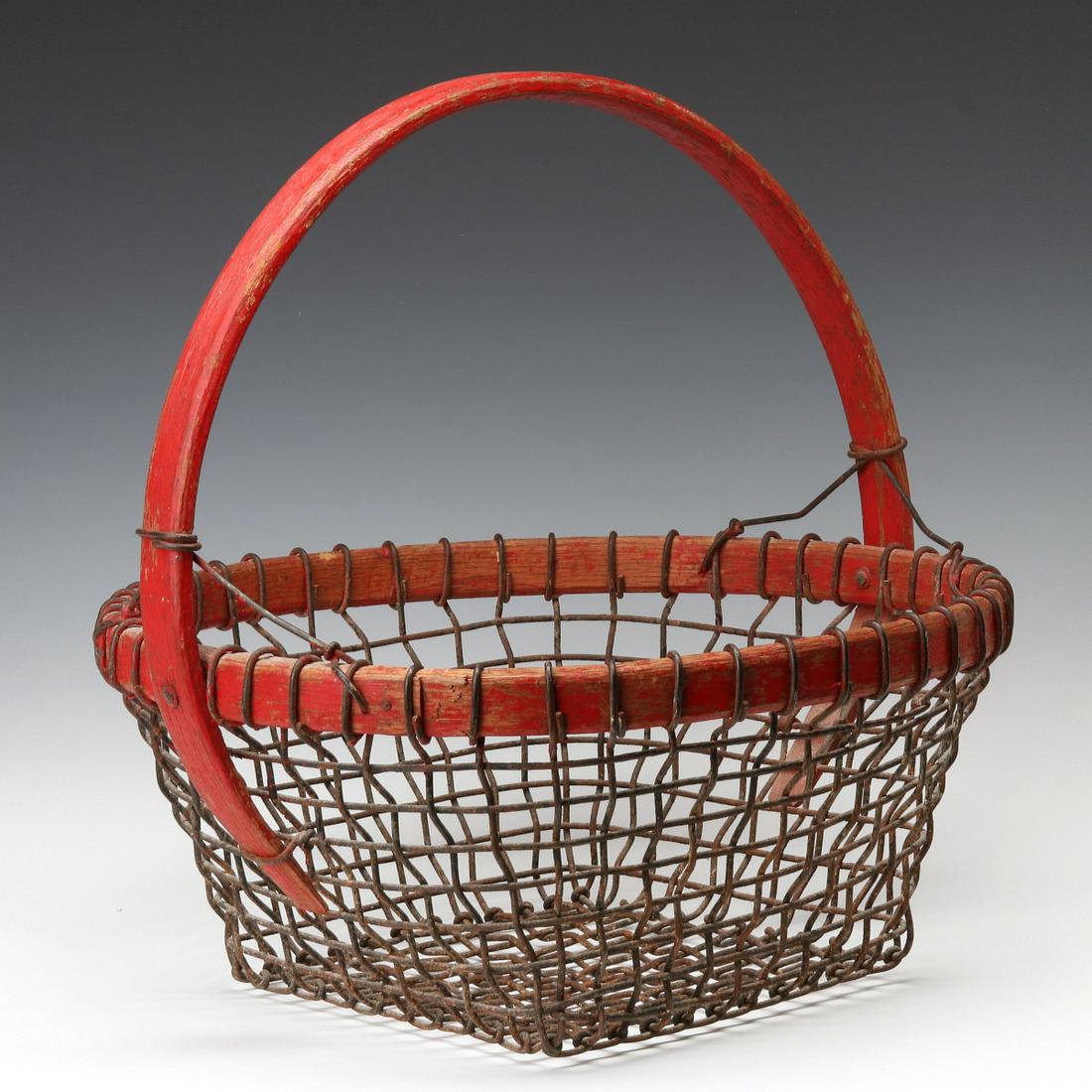 AN UNUSUAL WIRE MESH AND WOOD BASKET IN OLD RED STAIN: The heavy wire mesh incorporating a bent wood (Ash) rim and high arching handle in original red stain, circa late 19th century. Measures 16.5 x 16.5 inches. We happily provide seamless in-house packin