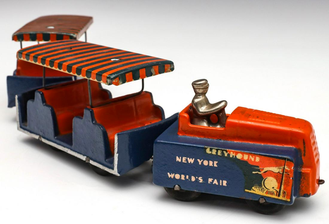 ARCADE GREYHOUND TROLLEY FOR 1939 NEW YORK WORLD'S FAIR: The iron tractor with original driver and graphics, the original Arcade decal and two passenger trolleys. Measures 2.25 x 3.25 and 2.5 x 4 inches. We happily provide seamless in-house packing and ship