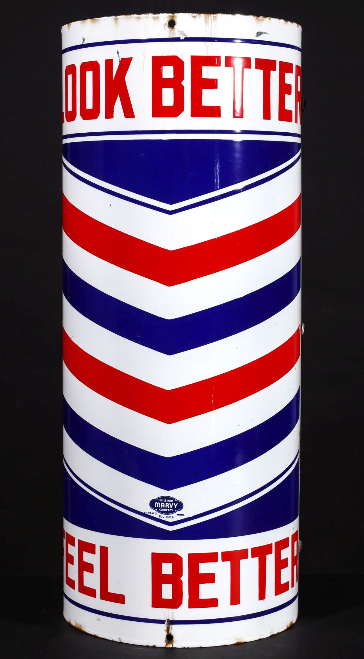 A HALF-ROUND POLE MOUNT PORCELAIN ENAMEL BARBER SIGN: The red, white and blue porcelain enamel sign reads 'Look Better, Feel Better,' signed William Marvy Company, St. Paul, Minn. No. 2416. Measures 24 x 9.5 x 5.25 inches. We happily provide seamless in-