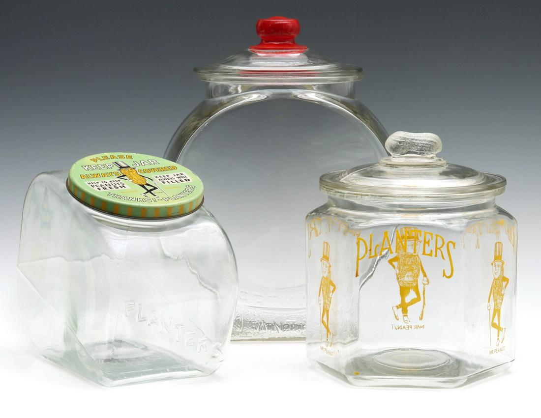 THREE PLANTER'S PEANUTS GLASS ADVERTISING JARS: Three jars, the largest example has a replacement lid embossed TOM'S. Sizes range from 8 x 5.25 x 10 to 13.5 x 7 x 9.75 inches. We happily provide seamless in-house packing and shipping services on ne