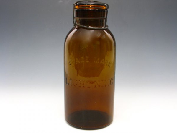 AN AMBER LIGHTNING TRADEMARK FRUIT JAR W/LID & LATC: Nice amber glass, embossed "Trade Mark Lightning" to side. Includes amber glass lid and metal latch. Measures 10.5 x 4.5 inches.