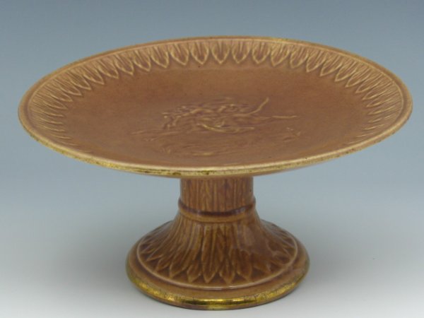 A MAJOLICA BOY RIDING LION PEDESTAL CAKE STAND: Dark pink, remnant gilt painted bottom rim. Measures 4 x 8 inches. Unmarked.
