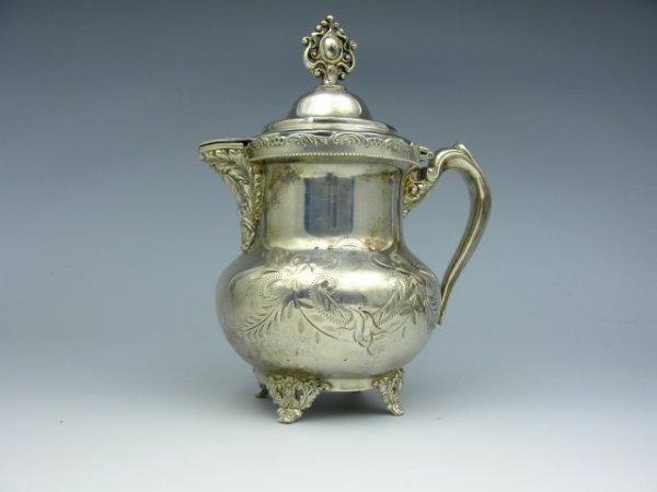 A VICTORIAN QUAD PLATE SYRUP PITCHER WITH LID: Stamped "Quadruple Queen CY. Sil. C2" to bottom. Four footed, hinged lid. Measures 7.5 x 5 inches with lid.