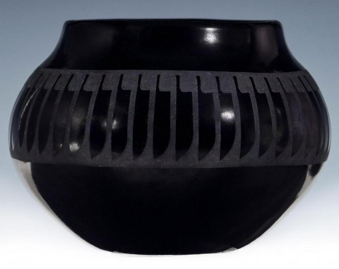 A SMALL SAN ILDEFONSO JAR SIGNED MARIA - POPOVI: Maria Martinez And Popovi Da Circa third quarter of the 20th century. The small two-tone black-on-black jar of small bulbous form encircled with a band of matte glaze polished back in pattern of repea
