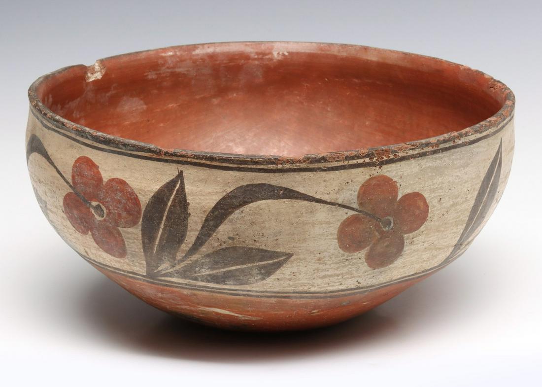 A LATE 19TH CENTURY ZIA PUEBLO POTTERY BOWL: Circa 1900. The deep bowl with stone-polished red slip interior, a band of meandering flowers painted on the exterior above a stone-polished red slip lower section and base. Measures 5.5 x 11.5 inches