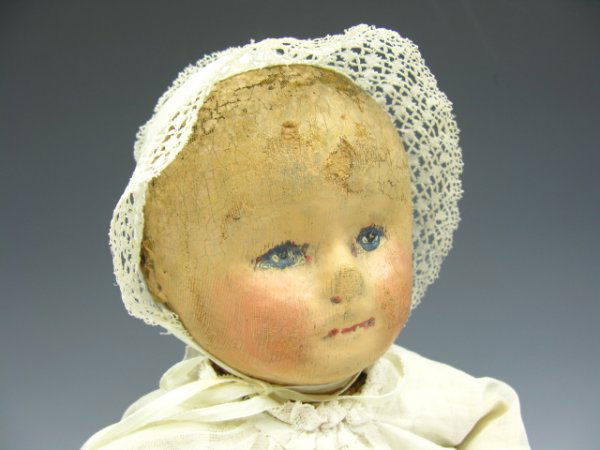 A MARTHA CHASE STOCKINETTE DOLL W/ ORIGINAL PAINT: About 20 inch long doll with painted hair and facial features. Jointed knees and elbows. Long white baptismal style dress.