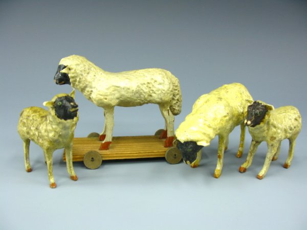 FOUR EARLY 1900'S PAPIER MACHE SHEEP FIGURES: Largest sheep on "Germany" marked wheeled wooden base, measures 3.5 x 4.5 x 1.5 inches, cardboard wheels. Other large sheep measures 2.5 x 4 inches, two smaller measure 2.5 x 3 inches. Two larger and