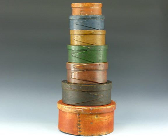 SEVEN GRADUATED PANTRY BOXES IN OLD PAINT: An assembled set of seven great bentwood boxes largest to smallest - 5.5 x 11.7 inches in old orange paint, 4 x 10 inch dark brown, 3.75 x 8 inch brown, 3.5 x 8 inch green, 2.75 x 6.75 inch dark tan, 