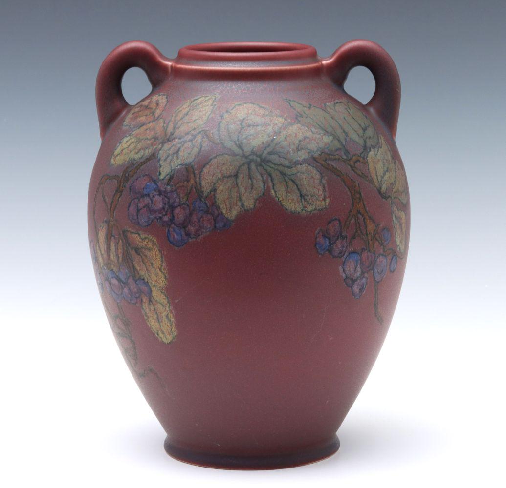 A ROOKWOOD MATTE VASE SIGNED CATHERINE COVALENCO: The amphora form vase with handles and prunus decoration of veined leaves, woody stems and fruit against a cherry red ground, impressed Rookwood monogram with flames and Roman numeral date for 1924 wi