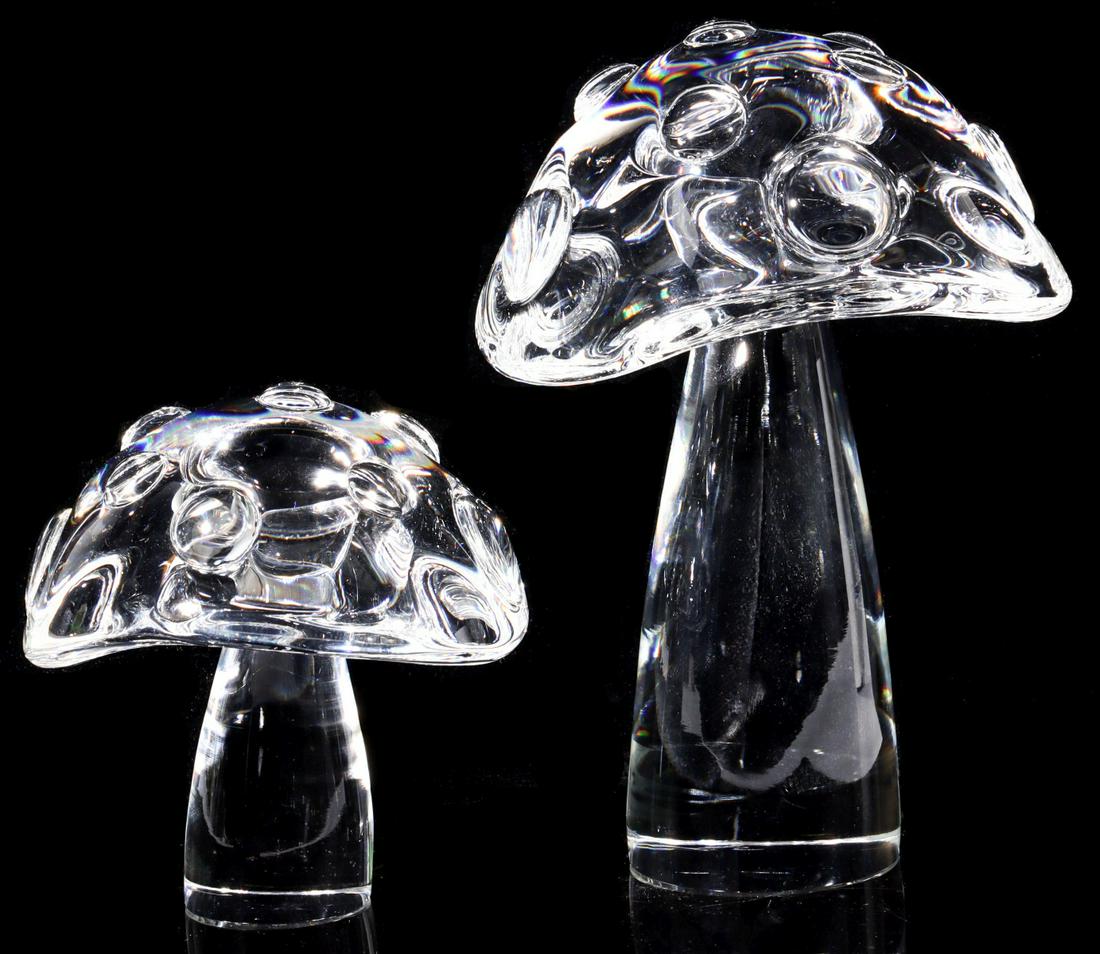 TWO DIFFERENT STEUBEN ART GLASS CRYSTAL MUSHROOMS: Circa 1971 Engraved signature on the base of each. Measure 4 and 6.5 inches. Provenance: The Topeka and Shawnee County Public Library We happily provide seamless in-house packing and shipping services