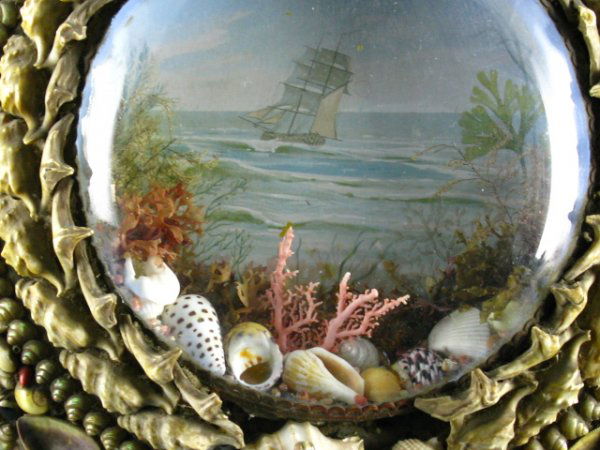 A VICTORIAN SHELL ART DIORAMA W/MARITIME SCENE: 10.75" diameter portal shaped diorama with Ship background and seashells and coral diorama, framed by shells. Flat back.
