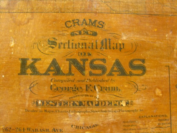 CRAM'S 1882 SWING-OUT ATLAS OF KANSAS: Measures 44 x 51 inches. Wood frame with heavy metal wall mounts. Front swings open to reveal 6 pages (2 swing-out), mostly geographic maps of the world. Interestingly shows Greenland & Franz Josef La
