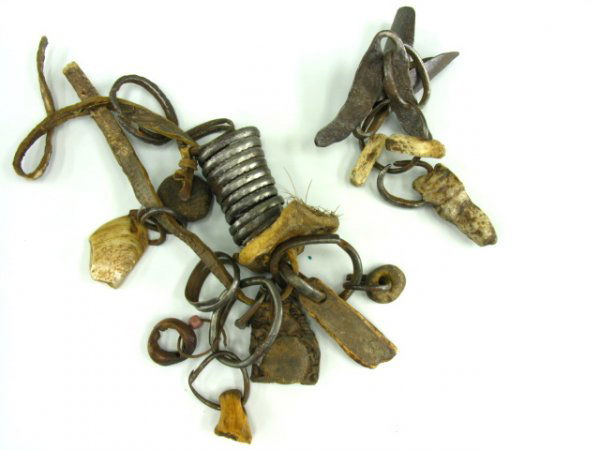 TRIBAL AFRICAN BRACELET WITH CHARMS OF FOUND OBJEC: Includes forged iron coils, a ring of animal hide, a bit of horn on iron ring. Leather pouch with seed, bits of wood and aquatic shells. Forged iron bell, no clapper. Assorted sizes, 3 to 5 inches. Co