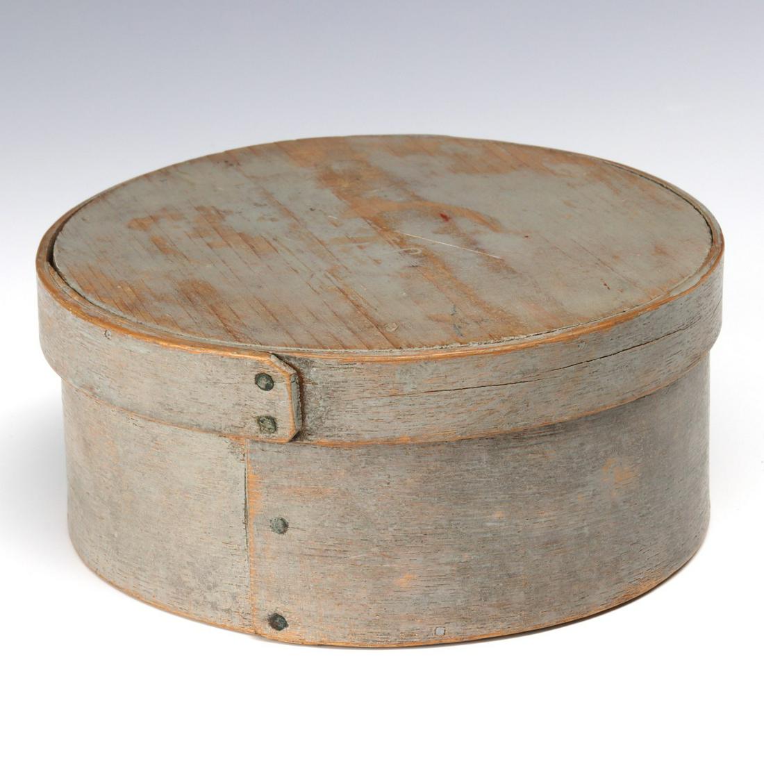 A 19TH CENTURY BENTWOOD PANTRY BOX IN OLD GRAY PAINT: The circular box in old milk paint, straight seams, constructed with copper tacks and wood pegs. Measures 3 x 6.75 inches. We happily provide seamless in-house packing and shipping services on nearly