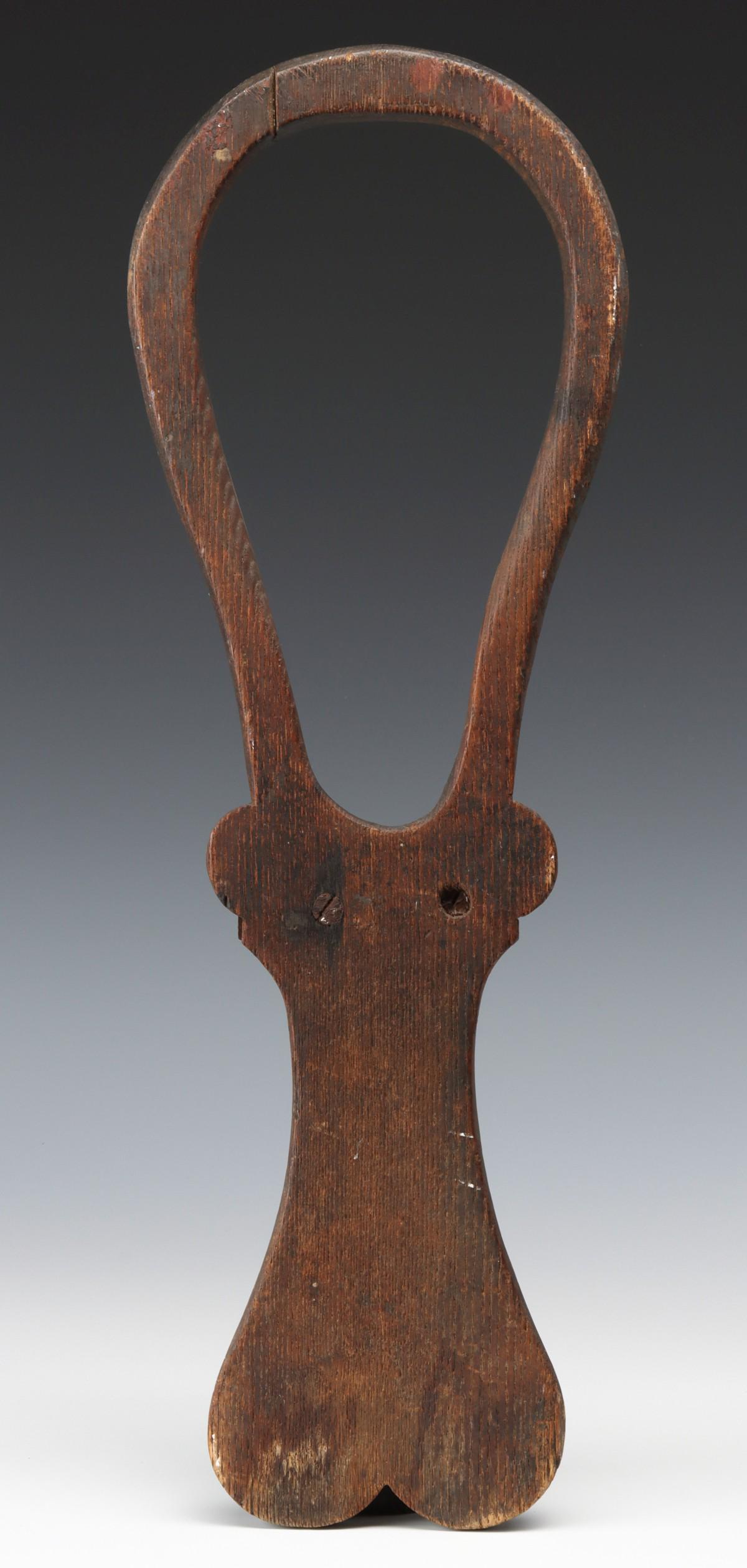 A CARVED ASH OR OAK BOOT JACK WITH HEART CUT-OUT: The hop form end with rounded ears over the central block and inswept sides before a heart shape end with whittled bevel on the underside, remnant traces of black stain most visible form the underside