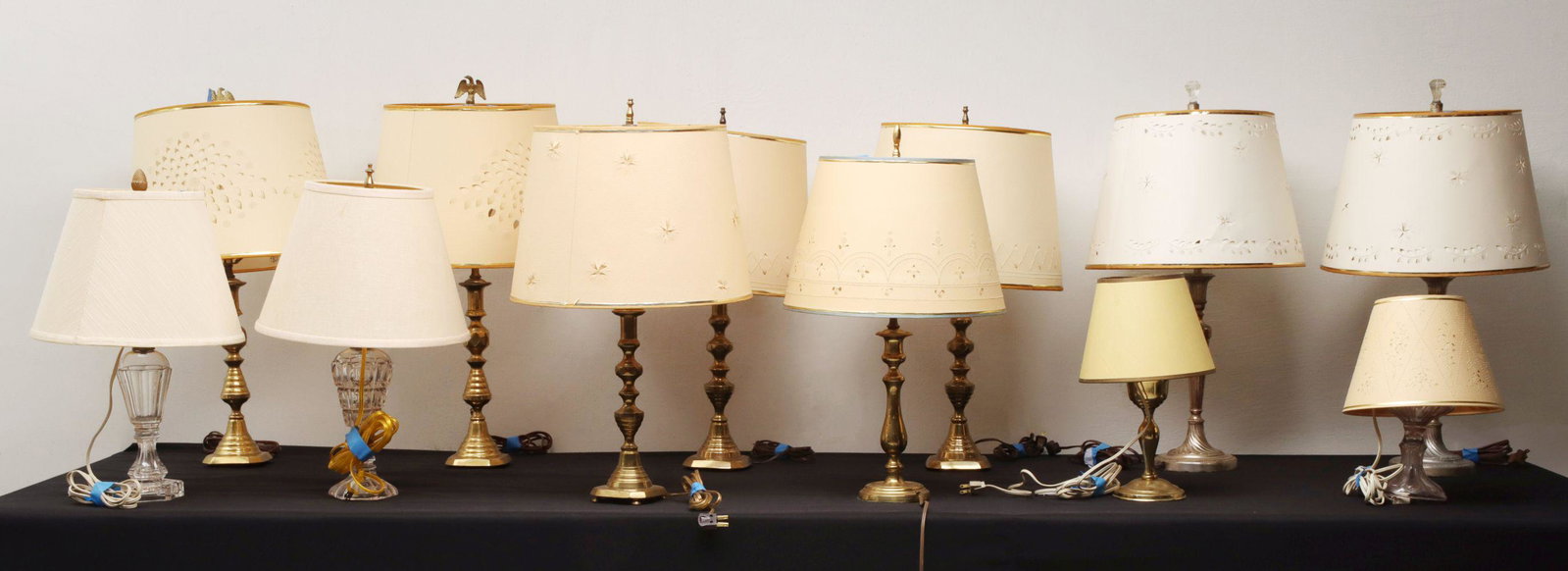 A COLLECTION OF PUSH-UP CANDLESTICK AND WHALE OIL LAMPS: The electrified 19th century brass push-up candlesticks and flint glass whale oil lamps with hand cut paper shades as shown, note the pairs with matching finials, plus a pair of later silver-plated Ad
