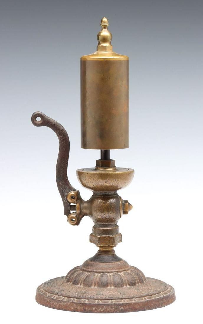AN ORNATE LATE 19TH CENTURY SINGLE NOTE STEAM WHISTLE: The acorn form nut atop brass bell with brass valve and iron side lever handle, currently displayed on an unrelated circular antique cast iron base, no markings found. Valve plate to top measures 8 in