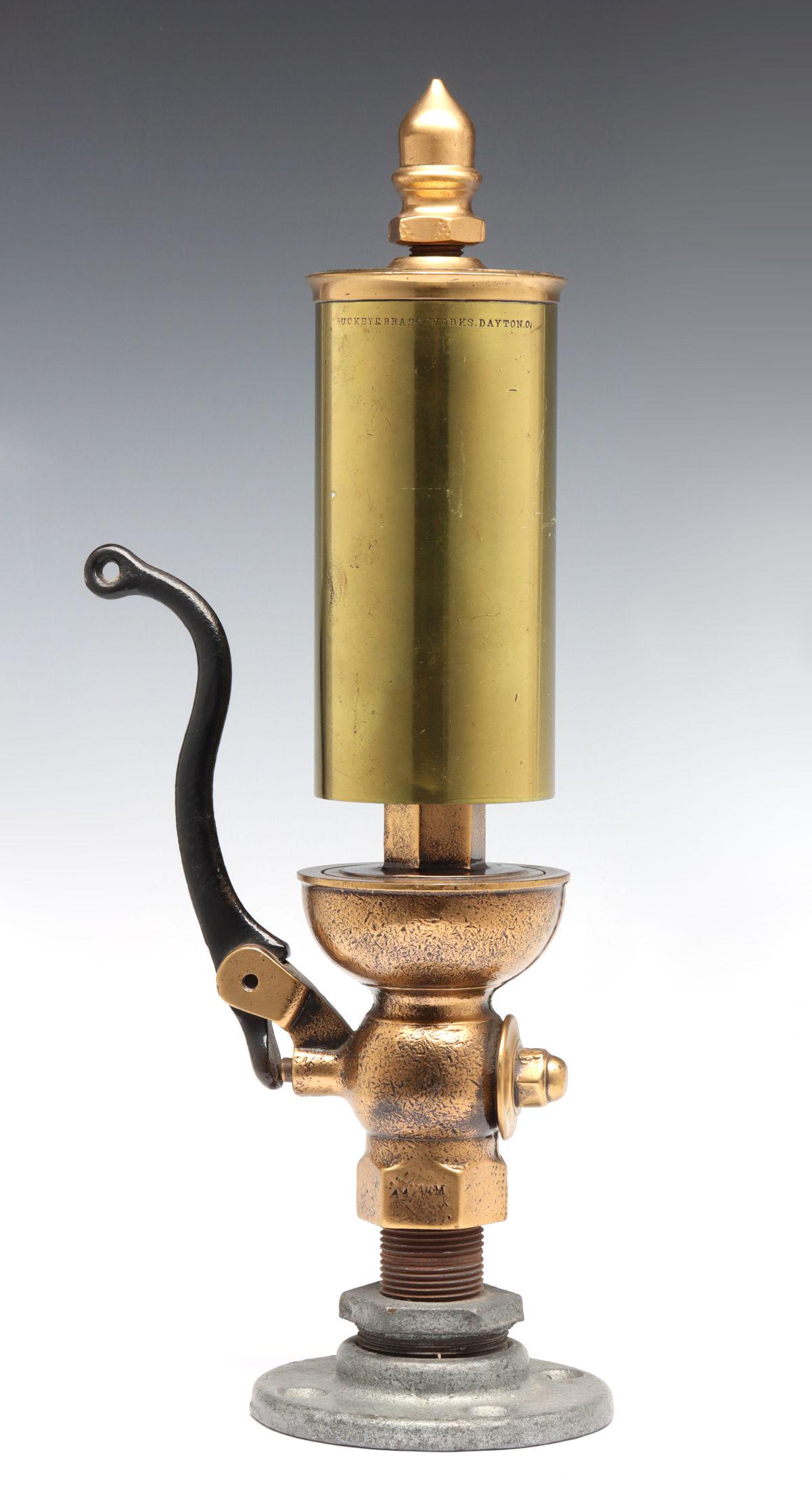 A SINGLE NOTE ALL BRASS STEAM WHISTLE SIGNED BUCKEYE: The nice brass example with acorn finial over the shiny cylindrical brass bell with sharply stamped mark of BUCKEYE BRASS WORKS. DAYTON. O, brass valve with iron under lever. Valve plate to top measur