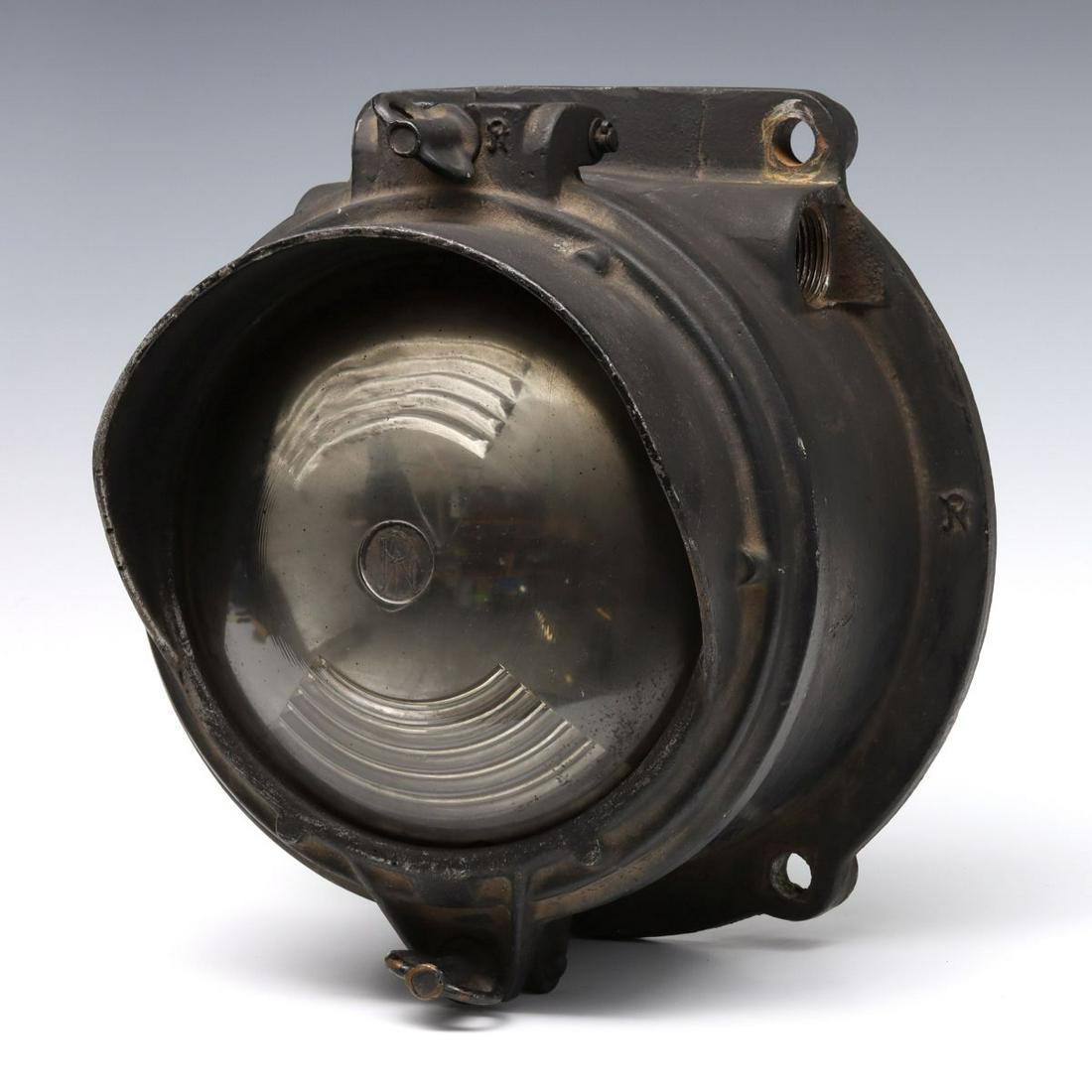 A PYLE NATIONAL CAST ALUMINUM LOCOMOTIVE TENDER LIGHT: The iron housing with hinged front bezel set with original glass lens having Pyle National logo cast in the glass and hood over the lens, additional Pyle logos cast throughout on the frame and housing