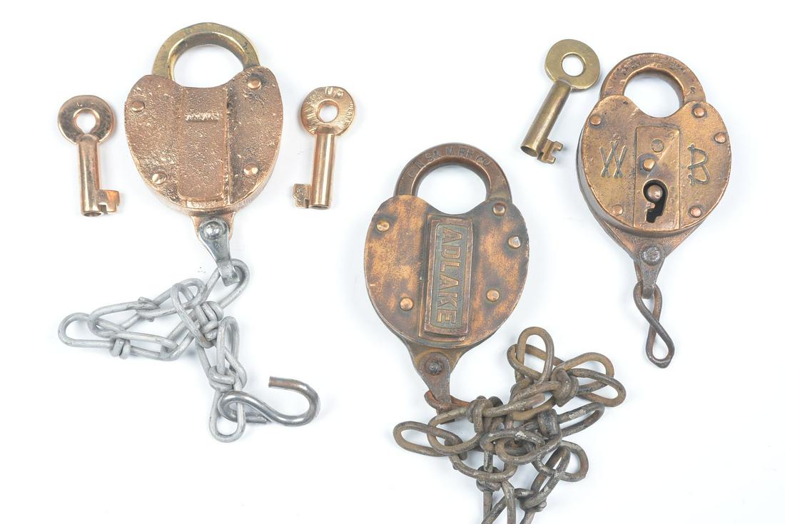 CAST BACK BRASS PADLOCKS WITH RAILROAD MARKINGS: Three railroad padlocks include: Raised lettering on the body UNION PACIFIC. signed Adlake on the back, two keys stamped UP; Stamped lettering CNS&M RR CO on the shackle for the Chicago North Shore an