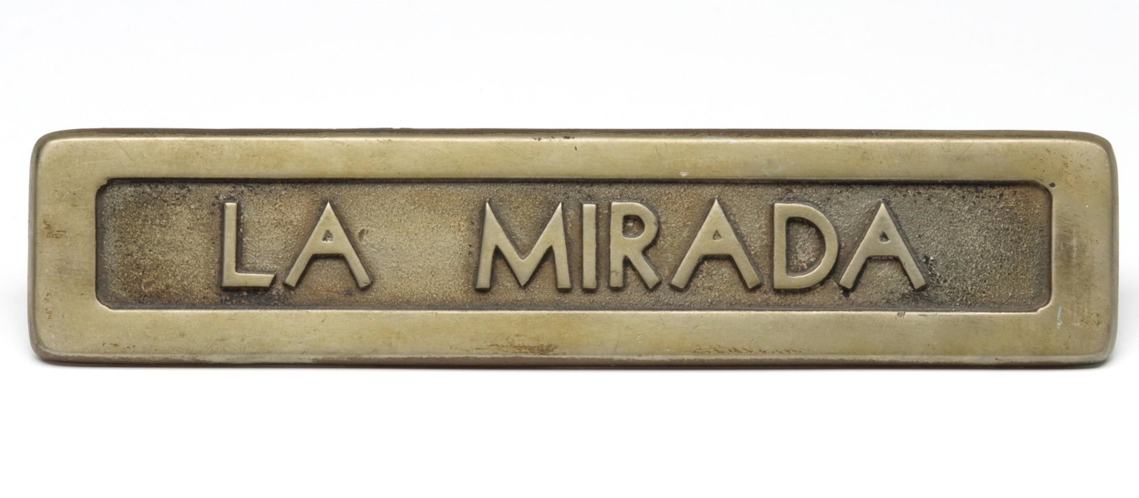A CAST BRASS CAR BADGE FOR SOUTHER PACIFIC LA MIRADA: The long rectangular nickel plated brass plaque with flat frame border centered by a pebble ground recessed area with block lettering of LA MIRADA in high relief. The LA MIRADA was a streamline passen