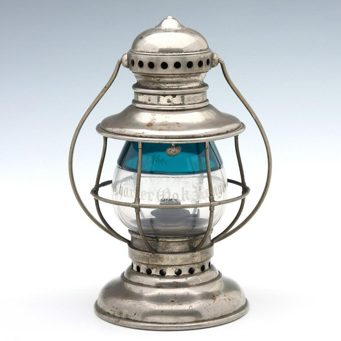 A PRESENTATION LANTERN ENGRAVED 'CHARTER OAK RANGE': The nickel-plated brass frame with swing handle and tall extended lip clear glass globe fused with teal green glass laid over the upper half, hand engraved inscription of ''Charter Oak Range'' in Old 