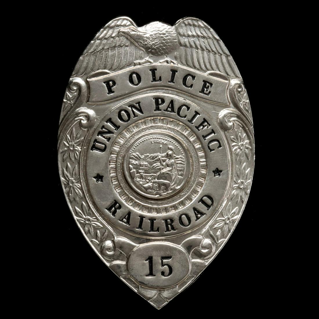 A SHIELD-FORM UNION PACIFIC RAILROAD POLICE BADGE: The rhodium plated shield with eagle surmount and flower heads up each side of the central roundel lettered UNION PACIFIC in recessed letters with black enamel paint around the central circular seal o