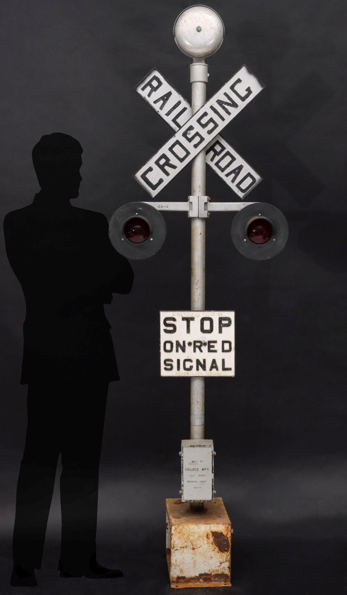VINTAGE MINIATURE STEAM RAILROAD CROSSING SIGNAL: The crossing signal with central standard topped by a signal bell above crossbuck sign and dual red lights side-by-side over square sign lettered STOP ON RED SIGNAL; manufactured by CHANCE MFG WICHITA