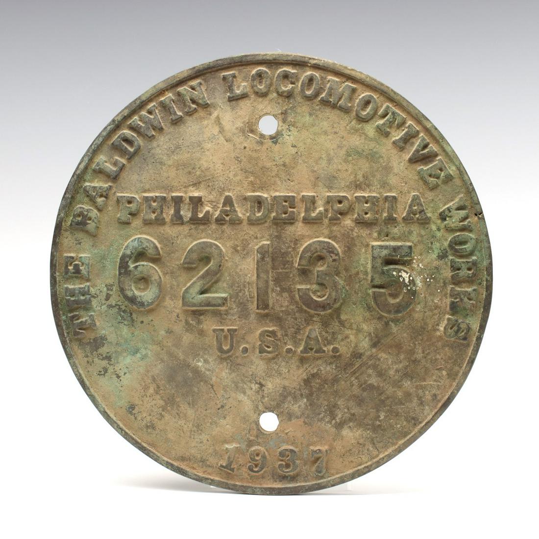 A BUILDER'S PLATE FOR NEW ORLEANS PUBLIC BELT SWITCHER: The circular brass plate with raised outer rim framing embossed letters and the construction number 62,135 along with the date 1937. The same type of plate as those found on steam engines is recorded 