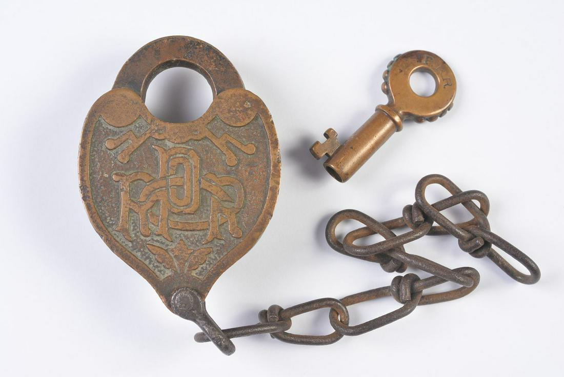 A CAST BACK PENNSYLVANIA RR PADLOCK W/ KNOBBY KEY: The fancy cast back lock with embossed lettering of PRR CO for Pennsylvania Railroad Company, shackle stamped SLAYMAKER, fancy tapered barrel key with scalloped edges stamped P.R.R. and signed Fraim.