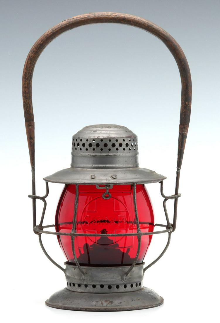 T.L. MOORE LANTERN WITH TALL CAST RED SANTA FE GLOBE: The wire frame with bellbottom base and embossed marking of SOLD ONLY BY T.L. MOORE SAN ANTONIO TEX PAT JUNE - 19 1909 on the cap, original wood handle, tall red glass globe with cast Corning maker's 